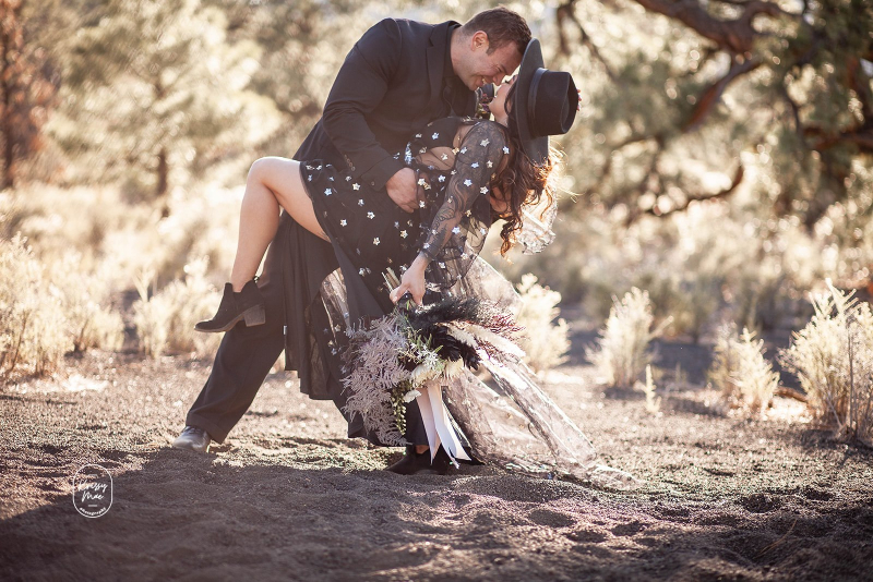Groom dips bride in black dress at desert elopement
