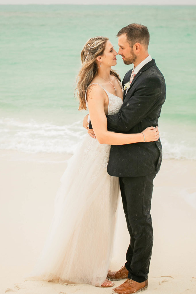 bride and groom holding each other on the beach